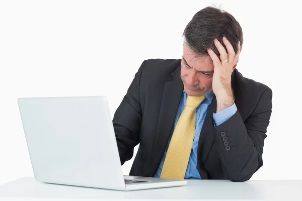 Homem perturbado sentado em sua mesa com um laptop — Fotografia de Stock
