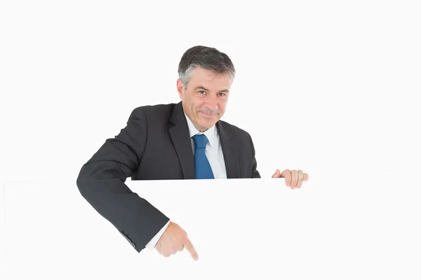 Smiling businessman pointing to board — Stock Photo, Image