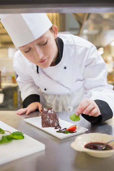 Chef feminino colocando hortelã com bolo — Fotografia de Stock