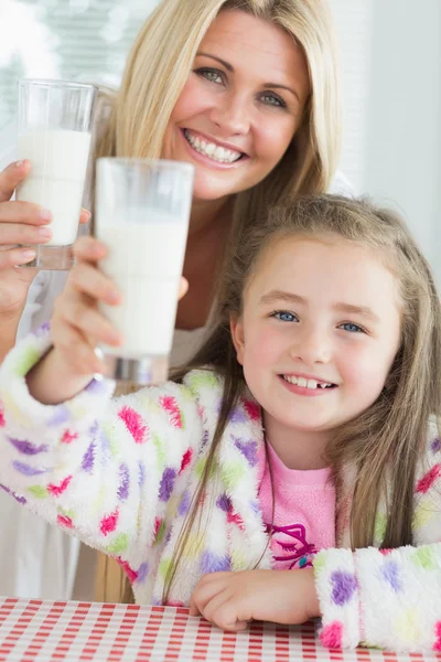 Mother and daughter raising milk glasses — Stock Photo, Image