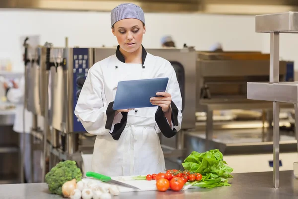 Серйозний шеф-кухар, використовуючи цифровий планшет біля овочів — стокове фото