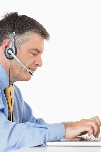 Empresario con escritura de auriculares en portátil —  Fotos de Stock