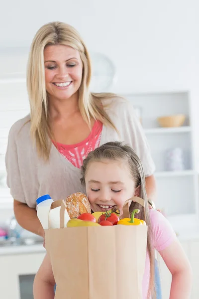 Dochter op zoek naar supermarkt tas met moeder kijken — Stockfoto