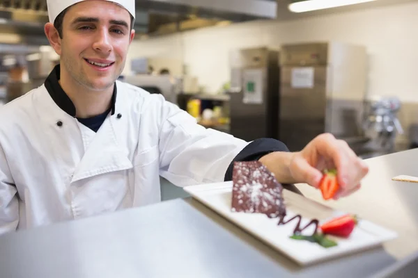 Smiling chef garnishing a slice of cake — Stock Photo, Image