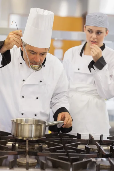 Maestro degustando su sopa de estudiantes con ella mirando ansiosamente —  Fotos de Stock