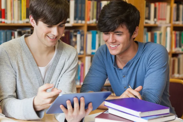 Students sitting at library desk looking at tablet pc — Stock Photo, Image