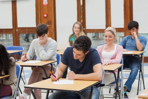 Students sitting at the exam room writing Stock Picture