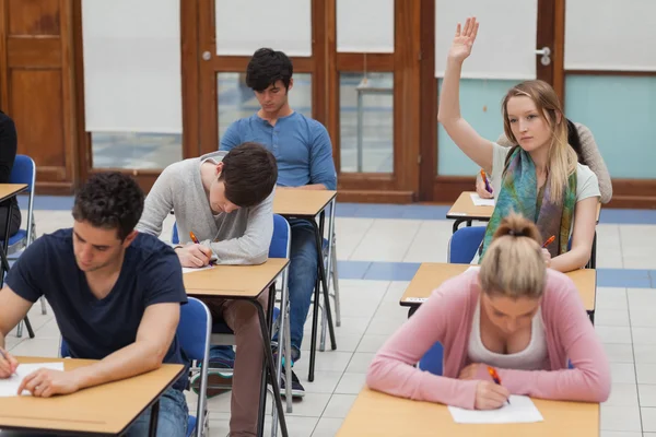 Woman raising hand during exam Stock Photo