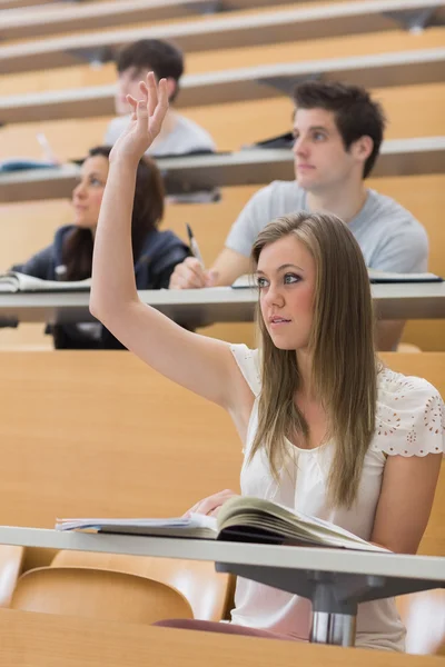 Woman sitting at the lecture hall with hand up Stock Image