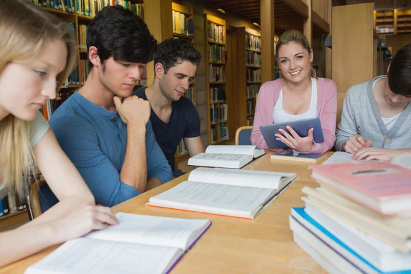 Woman holding a tablet pc sitting at table in library Stock Photo