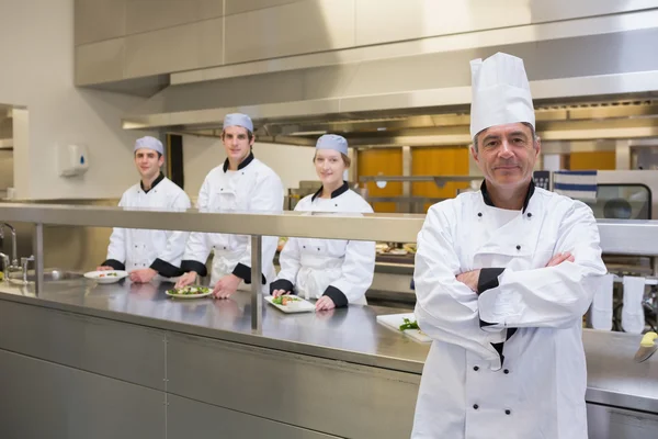 Chefe de cozinha de pé com a equipe atrás dele — Fotografia de Stock