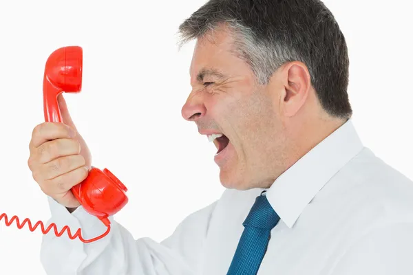 Businessman screaming in phone receiver — Stock Photo, Image