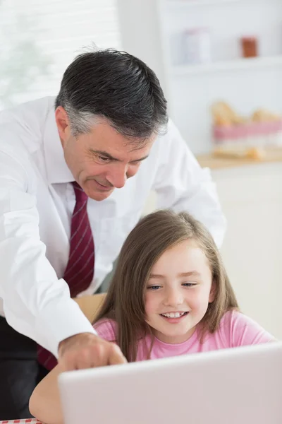 Père pointant quelque chose sur l'ordinateur portable de sa fille et souriant — Photo