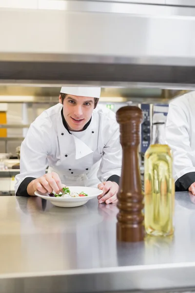 Chef looking up from garnishing salad — Stock Photo, Image