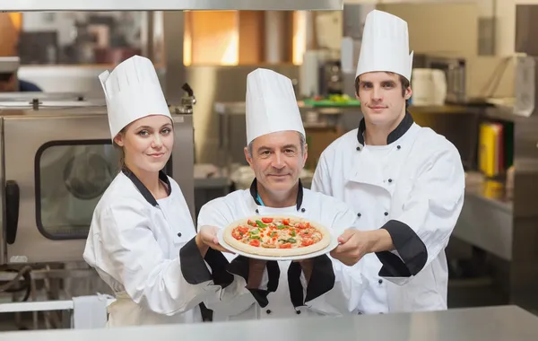 Tre kock innehar en pizza — Stockfoto