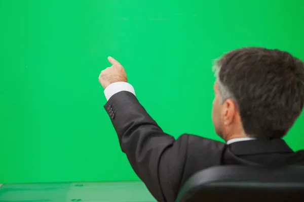 Empresário apontando em uma parede verde — Fotografia de Stock