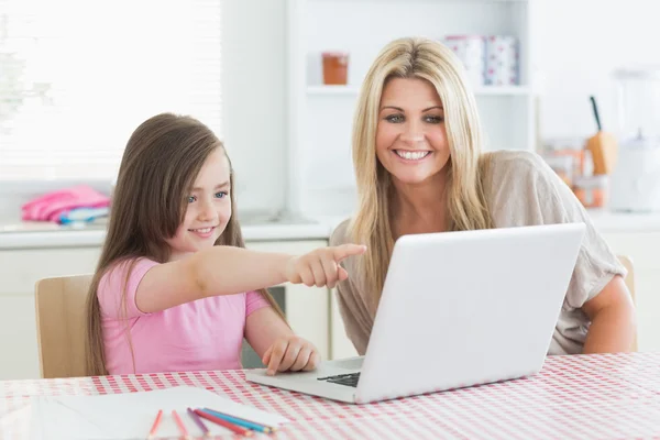 Filha apontando para laptop com mãe — Fotografia de Stock