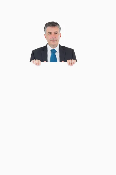 Smiling businessman looking over top of board — Stock Photo, Image