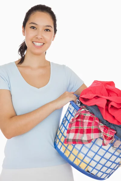 Mujer sonriente sosteniendo una cesta llena de ropa sucia —  Fotos de Stock