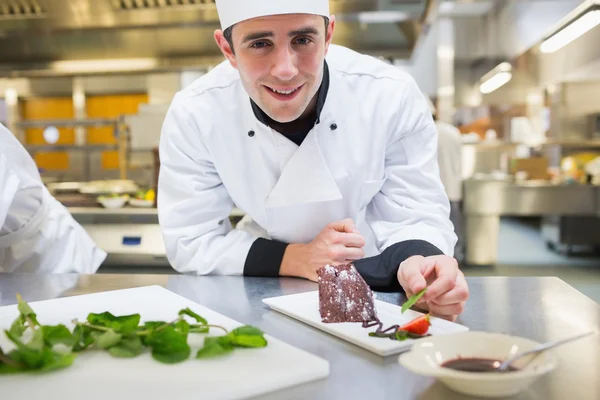 Chef sonriente poniendo menta con su postre — Foto de Stock