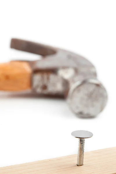 Metade do prego colando em uma prancha e um martelo atrás — Fotografia de Stock