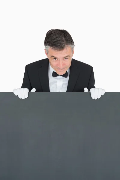 Smiling waiter behind grey board — Stock Photo, Image