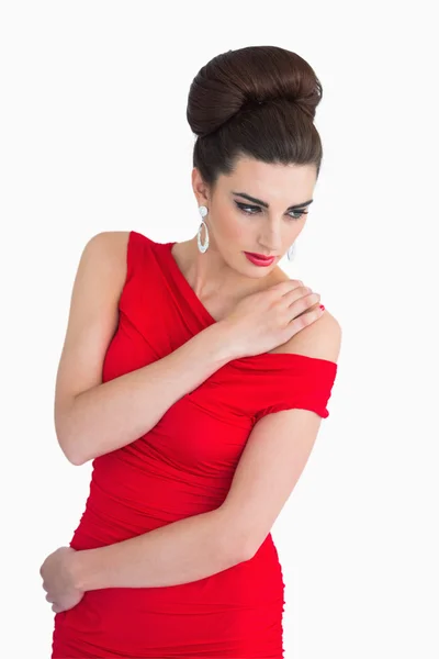 Kobieta w czerwonej sukience, trzymając jej ramię — Zdjęcie stockowe