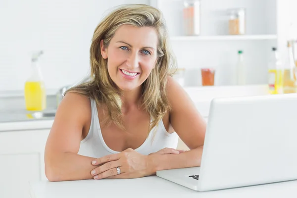 Mujer sentada en la cocina y usando laptop — Foto de Stock