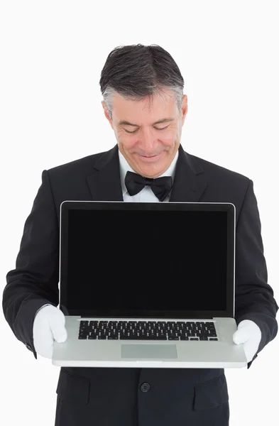 Šťastný číšník nám ukazuje něco na laptop — Stock fotografie