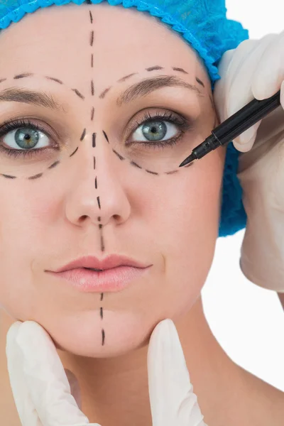 Doctor drawing on woman's face for face lift — Stock Photo, Image