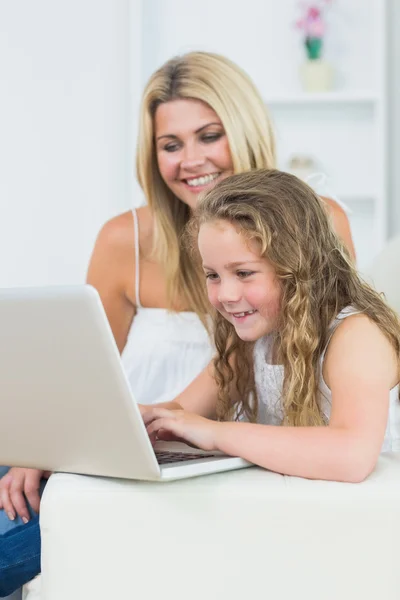 Mother and daughter sitting on the sofa with laptop — Stockfoto