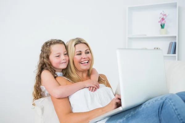 Filha abraçando a mãe cujo trabalho no laptop — Fotografia de Stock