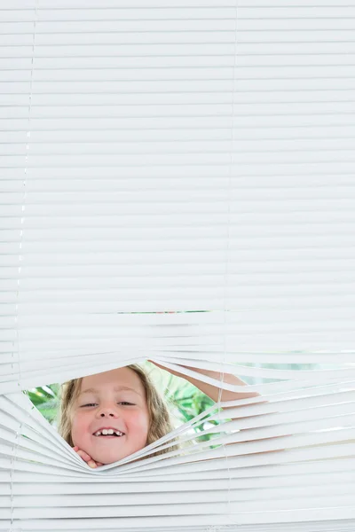 Meisje gluren uit blinds — Stockfoto