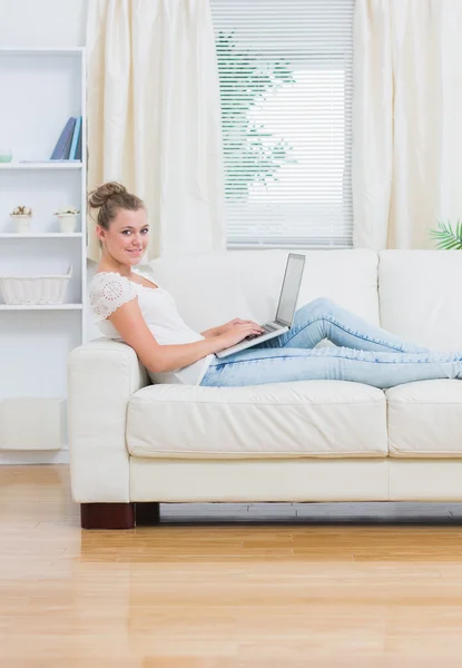 Mulher usando laptop deitado no sofá — Fotografia de Stock