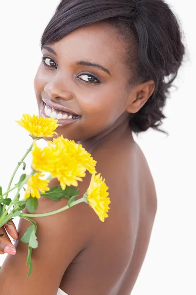 Frau blickt über ihre Schulter und hält Blumen in der Hand — Stockfoto