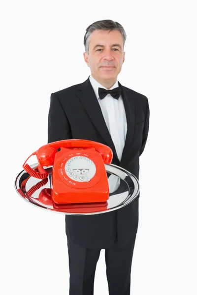 Välklädda servitör hålla en telefon på en silverbricka — Stockfoto