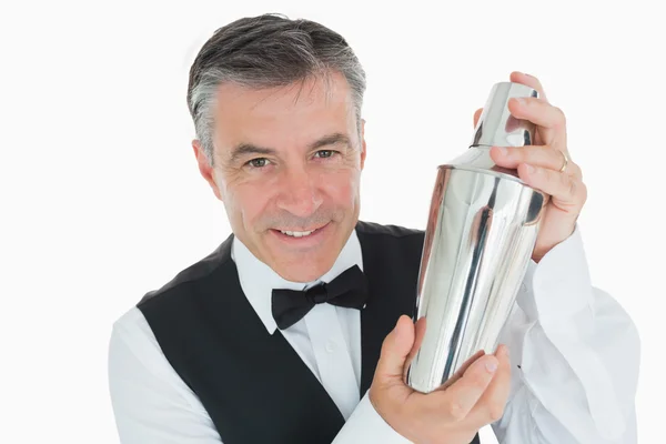 Camarero sonriente sacudiendo bebida en coctelera — Foto de Stock