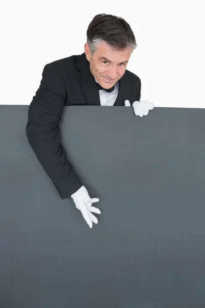 Smiling waiter presenting grey board — Stock Photo, Image