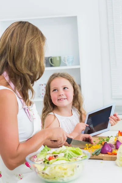 Мати ріже овочі з дочкою, використовуючи планшет — стокове фото