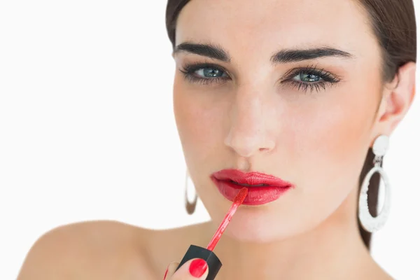 Mujer aplicando brillo labial rojo — Foto de Stock