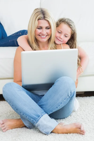 Mother sitting on the floor while her daughter hugging her from — Stock Photo, Image