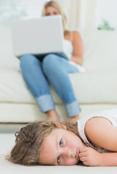 Tochter ruht sich auf dem Boden aus, während ihre Mutter Notizbuch benutzt — Stockfoto