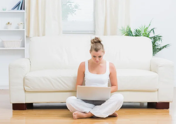 Blonde zittend op de vloer met laptop — Stockfoto