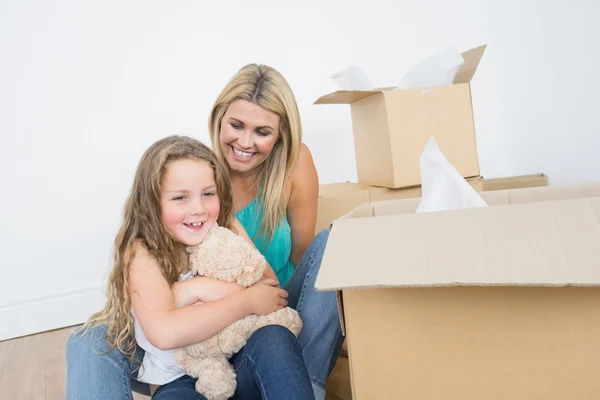 Child holding a teddy bear near her mother — Stock Photo, Image