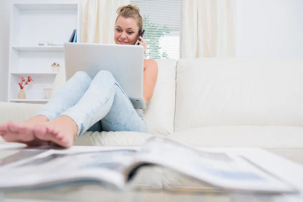 Mulher chamando e usando laptop na sala de estar — Fotografia de Stock