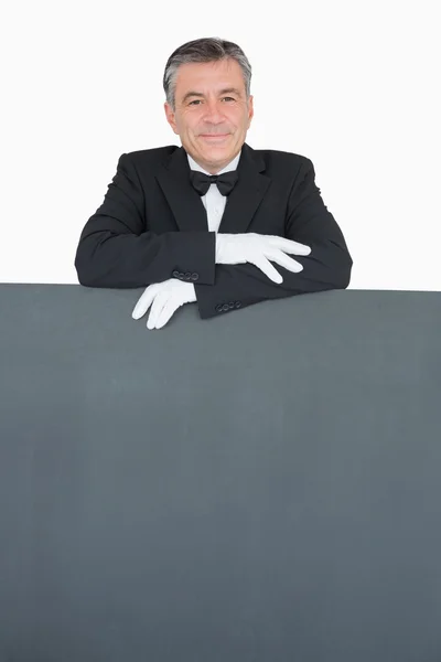 Man in suit leaning on grey board — Stock Photo, Image