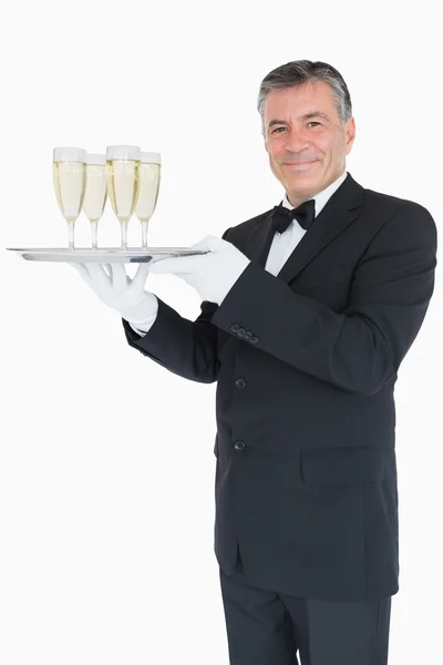 Leende servitör innehar fack med glasögon med champagne — Stockfoto