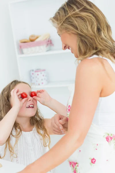 Hija usando tomates cherry para los ojos — Foto de Stock