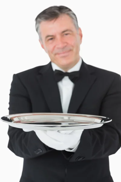 Smiling waiter holding a silver tray with both hands — Stock Photo, Image