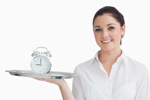 Waitress holding alarm clock on a tray — Stock Photo, Image